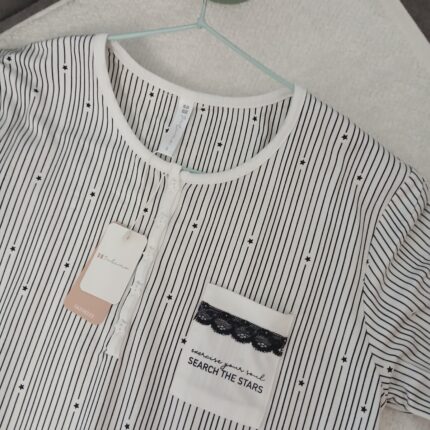 Robe de nuit Étoile Noir 🌛
Robe de nuit élégante à rayures fines et motifs étoiles, avec col boutonné et poche décorée de dentelle noire.
Matière douce et légère, idéale pour des nuits confortables avec une touche chic.